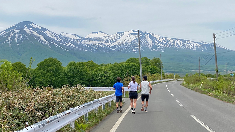 [写真]八甲田山を視界においてランニングするアウローラのメンバー