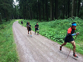 [写真]新田佳浩選手を先頭にスキーポールジャンプする選手たち