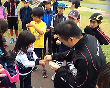 [写真]子供たちにリオパラリンピック記念コインを配る久保恒造選手