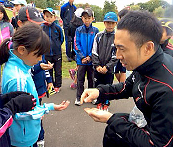 [写真]子供たちにリオパラリンピック記念コインを配る久保恒造選手