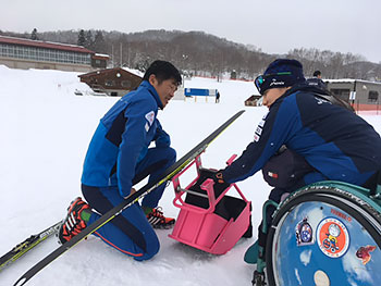 [写真]新しいスキー板を取り付けようとする新田佳浩選手と新田のんの選手