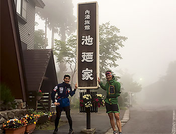 [写真]池迺家の看板の脇に立つ岩本選手、新田選手