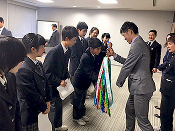 [写真]足立区千寿桜堤中学校の見皆さんから千羽鶴を受け取る新田選手