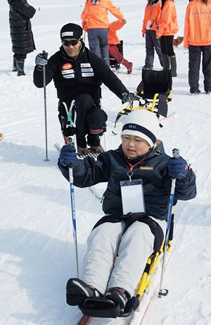 [写真]第1回スキー教室でシットスキー初体験の子供と長田弘幸選手