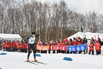 [写真]応援団の前を滑走する新田選手