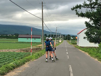 [写真]新田選手が阿部選手に技術アドバイスをしながら滑走