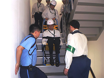 [写真]避難訓練 車いすを操作してもらい階段を降りる