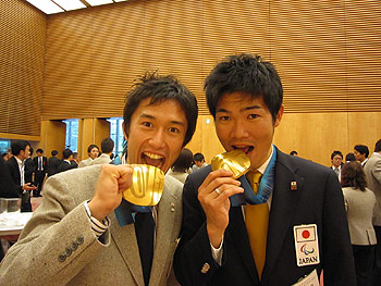 [写真]小林範仁選手と新田佳浩。メダルを食べるポーズ
