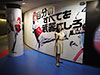 [写真]都営大江戸線国立競技場駅パラリンピック競技展示のパラテコンドーのポスターの前でポーズをとる太田渉子